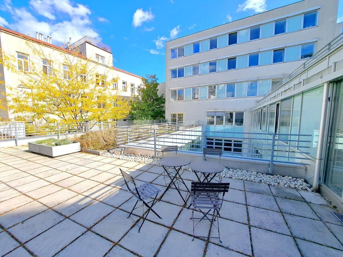 Geräumige Dachterrasse mit Sitzgelegenheiten, Pflanzen und einem weiten Blick auf die umliegenden Gebäude.