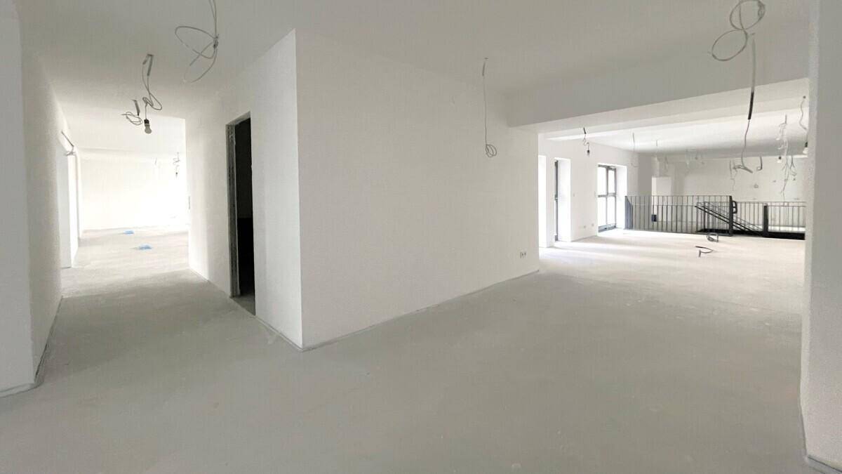 Heller Flurbereich, der zu einem großen, offenen Gewerberaum mit Galerie führt.