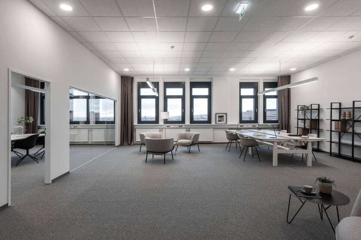 Weitläufiges offenes Büro mit flexiblen Arbeitsbereichen, bequemen Sitzgelegenheiten und viel Tageslicht.