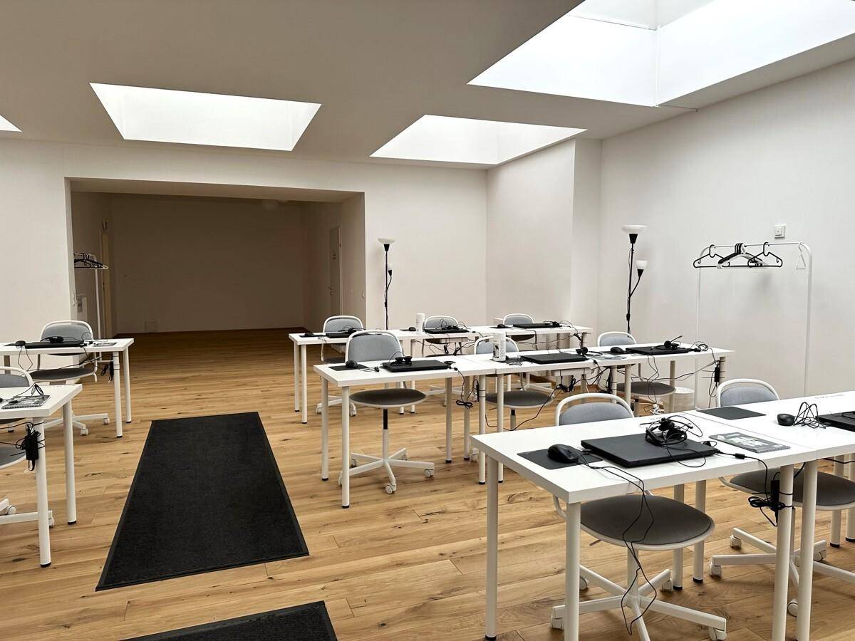 Geräumiger Bürobereich mit zahlreichen Arbeitsplätzen, Holzboden und großen Deckenfenstern für viel Licht.