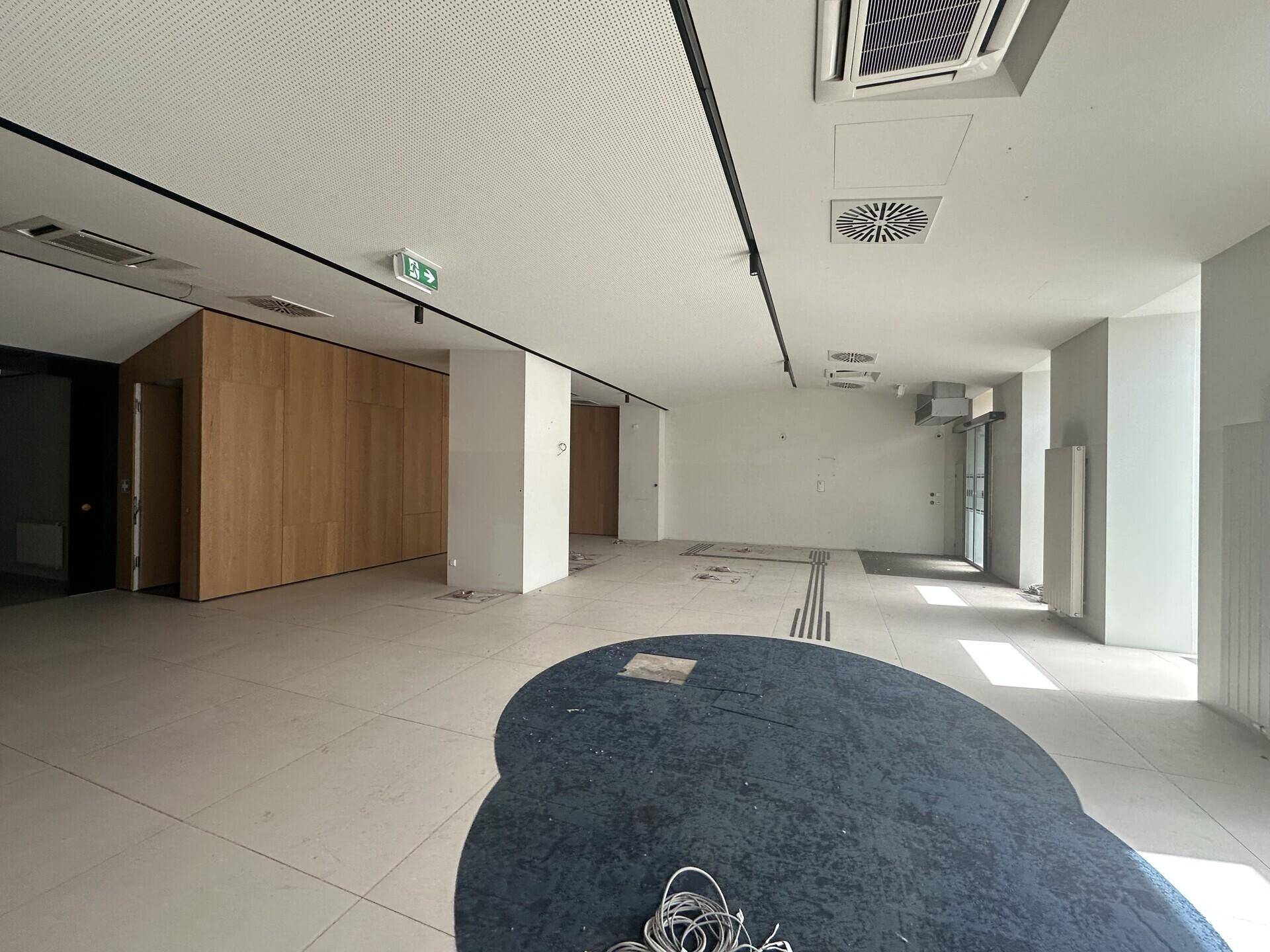 Großer, offener Geschäftsraum mit Fliesenboden, Holzwänden und moderner Deckenbeleuchtung.