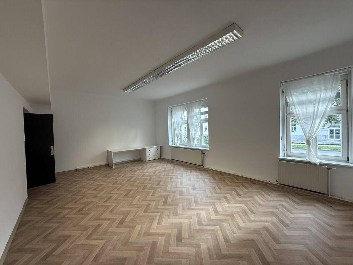 Heller, leerer Büroraum mit Fischgrätparkett und großen Fenstern, bereit zur individuellen Gestaltung.