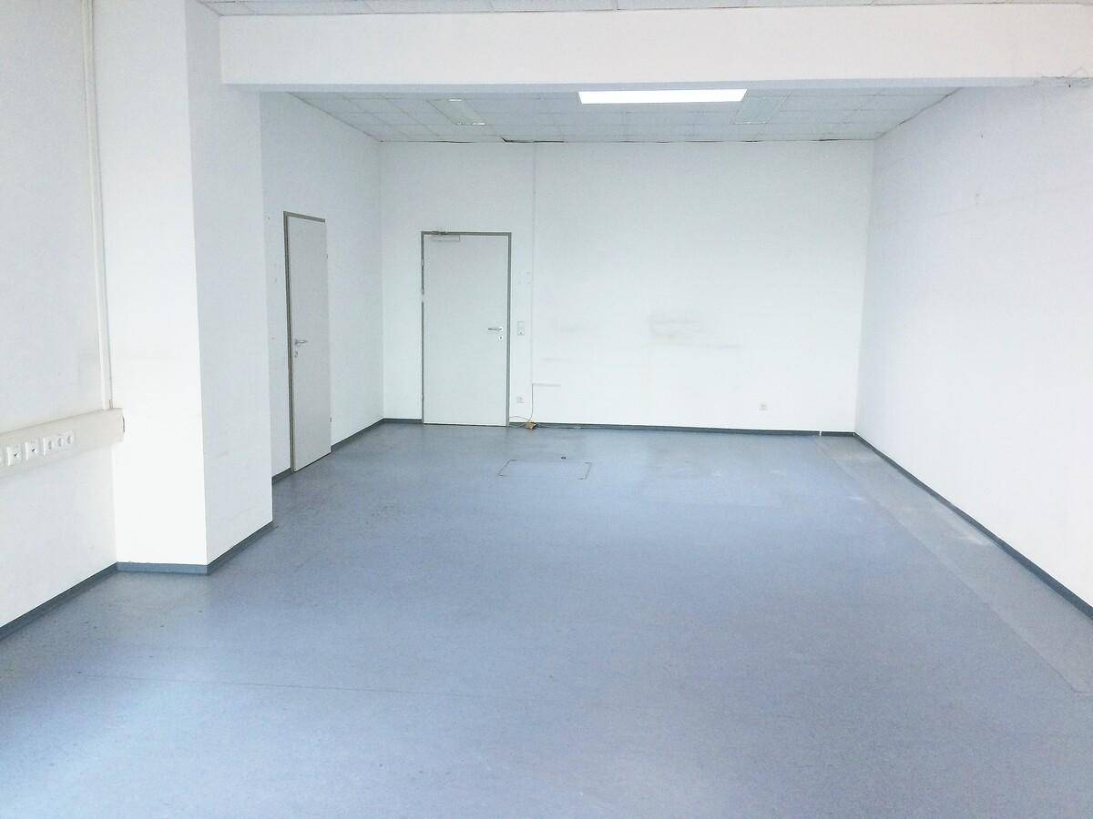 Geräumiger, leerer Raum mit blauem Vinylboden und weißen Wänden, bereit für die individuelle Gestaltung.