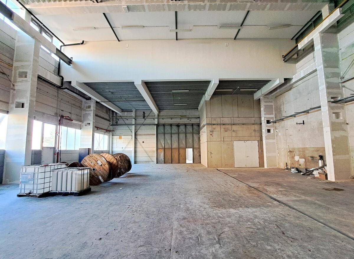 Weitläufige Lagerhalle mit hohen Decken, Betonboden und viel Platz für industrielle Nutzung.