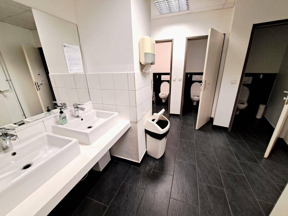Funktionale Badezimmer mit zwei Waschbecken, großen Spiegeln und mehreren Toilettenkabinen.