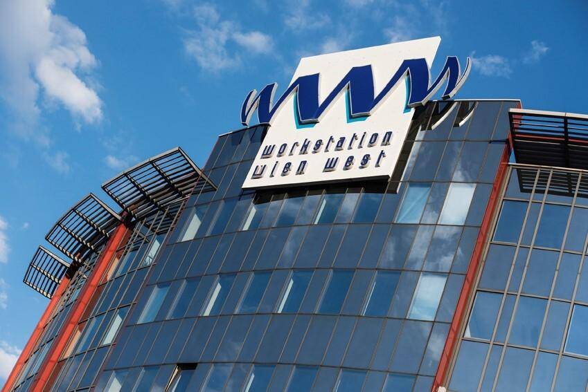 Detailansicht der geschwungenen Glasfassade eines modernen Bürokomplexes mit dem markanten Firmenlogo.