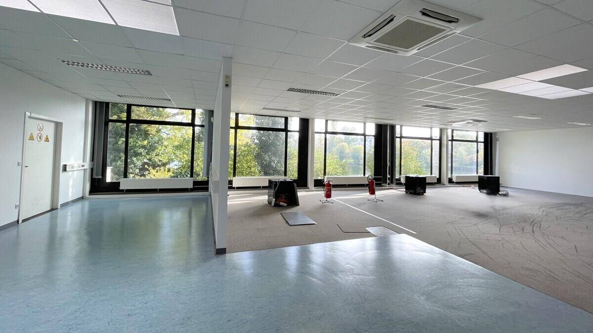 Geräumiger Gewerberaum mit gemischtem Bodenbelag und großen Fenstern, die einen weiten Seeblick ermöglichen.