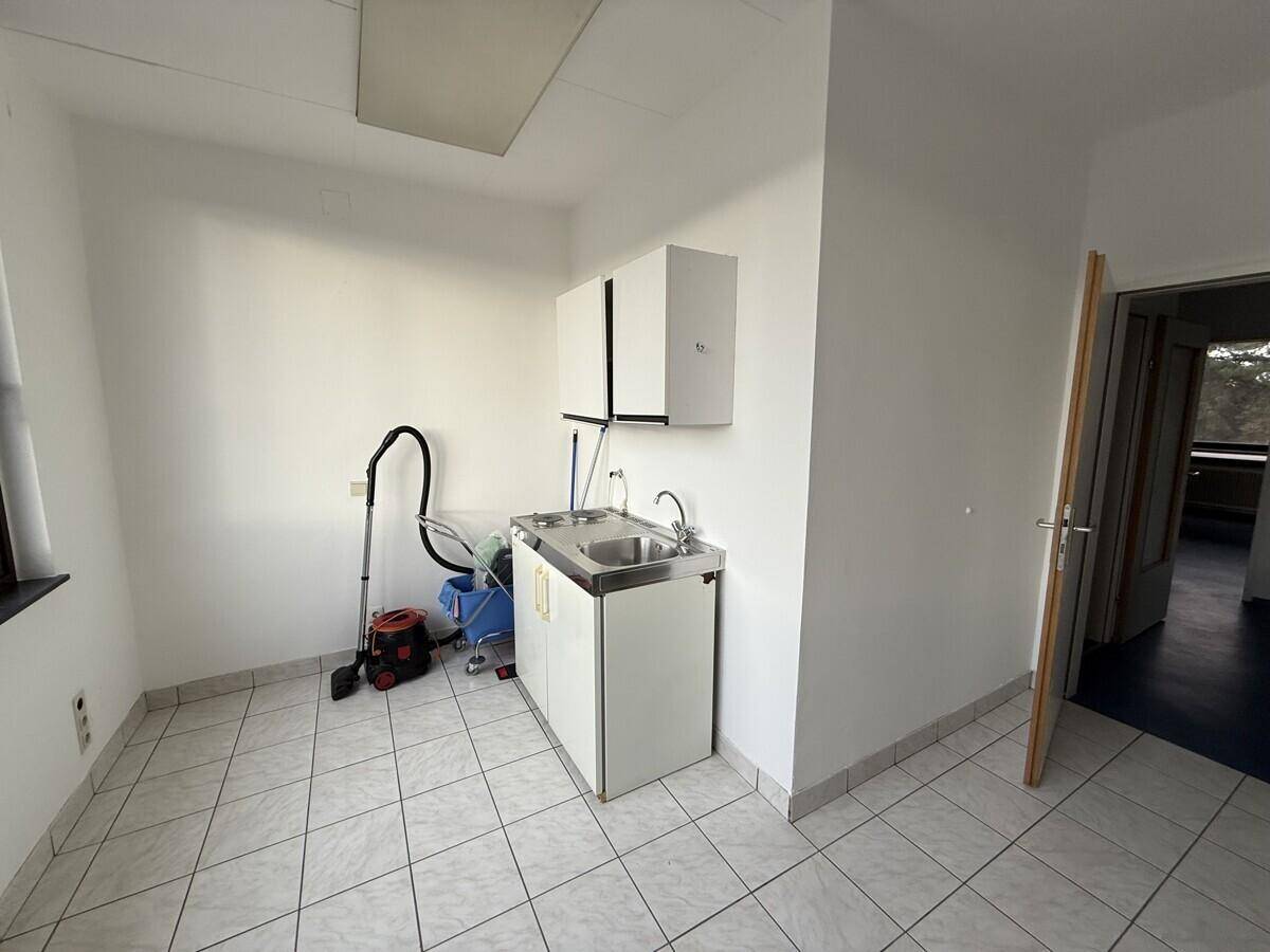 Hauswirtschaftsraum mit Waschbecken, Fliesenboden und Stauraum, ideal für Reinigungsarbeiten.