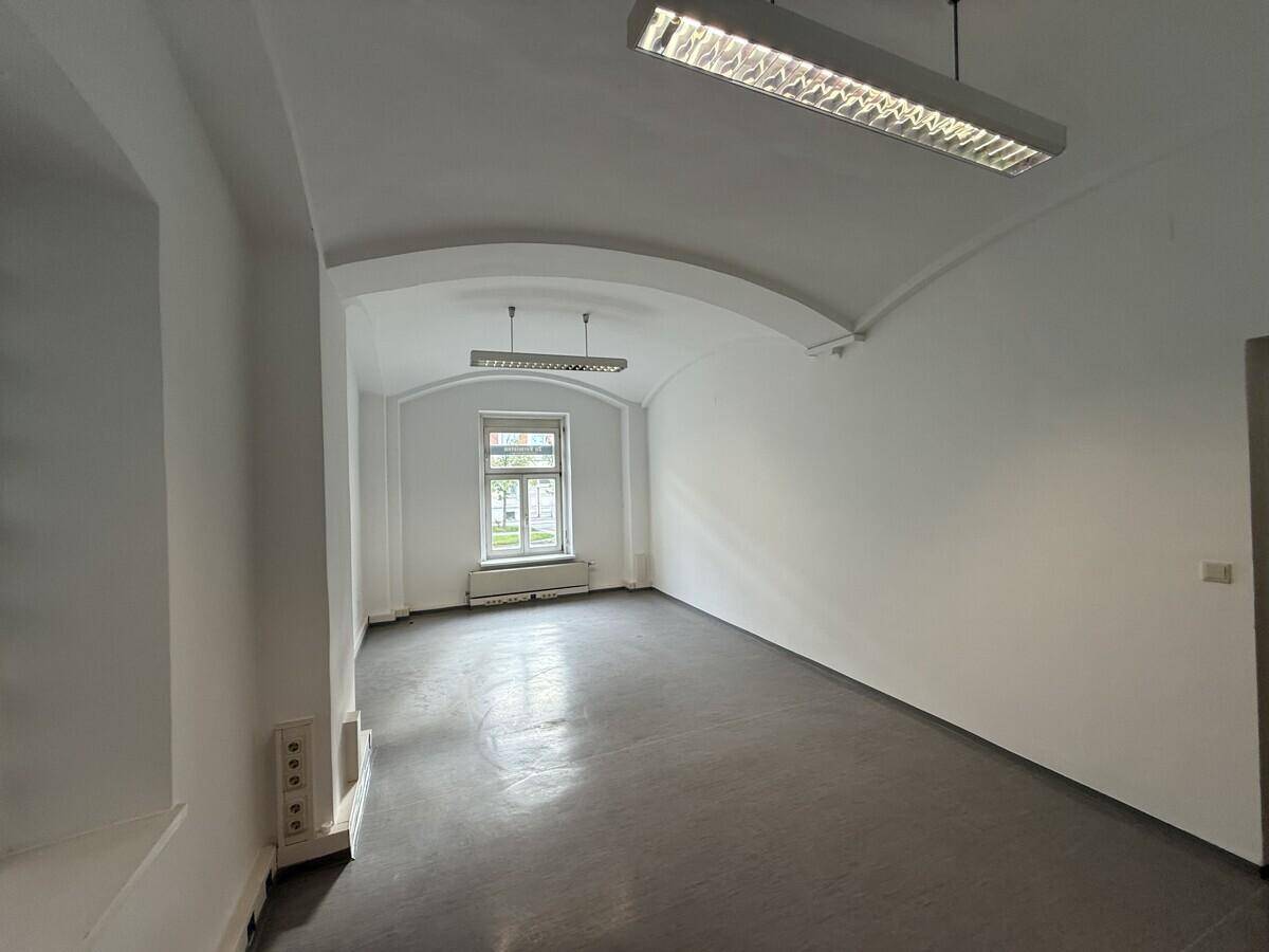 Geräumiger, leerer Raum mit Gewölbedecke und dunklem Boden, ideal für Büro oder Lager.