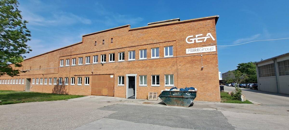 Außenansicht des großen Backsteingebäudes mit GEA-Logo, Fenstern und Zufahrtsbereich bei Tag.