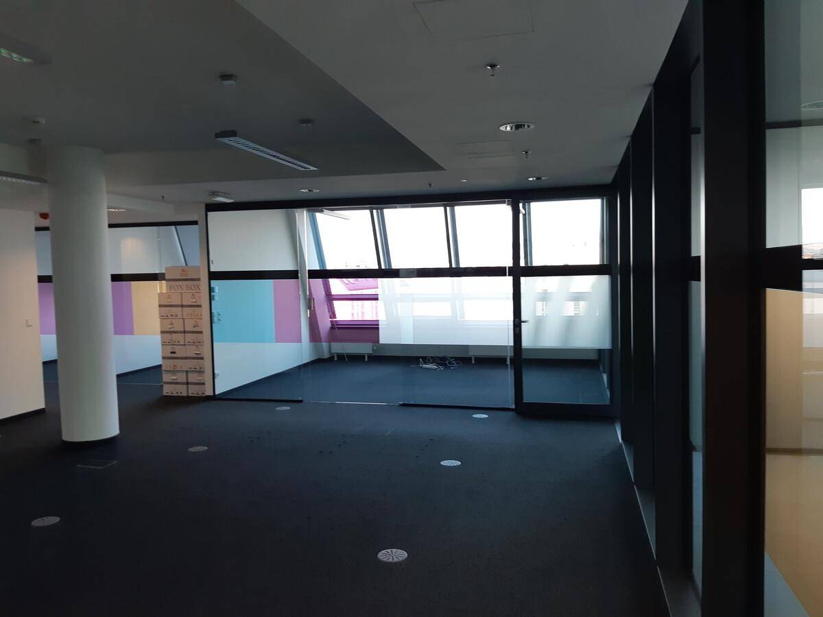 Leeres Büro mit dunklem Teppichboden, Glaswänden und Fenstern mit farbiger Sichtschutzfolie.