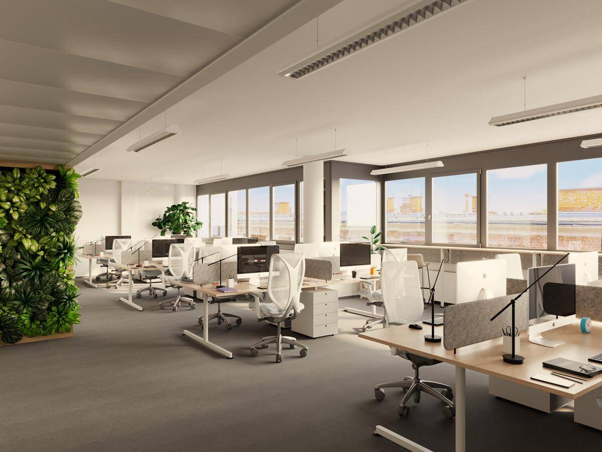 Großes, offenes Büro mit modernen Arbeitsplätzen, grüner Wand und viel Tageslicht durch große Fenster.
