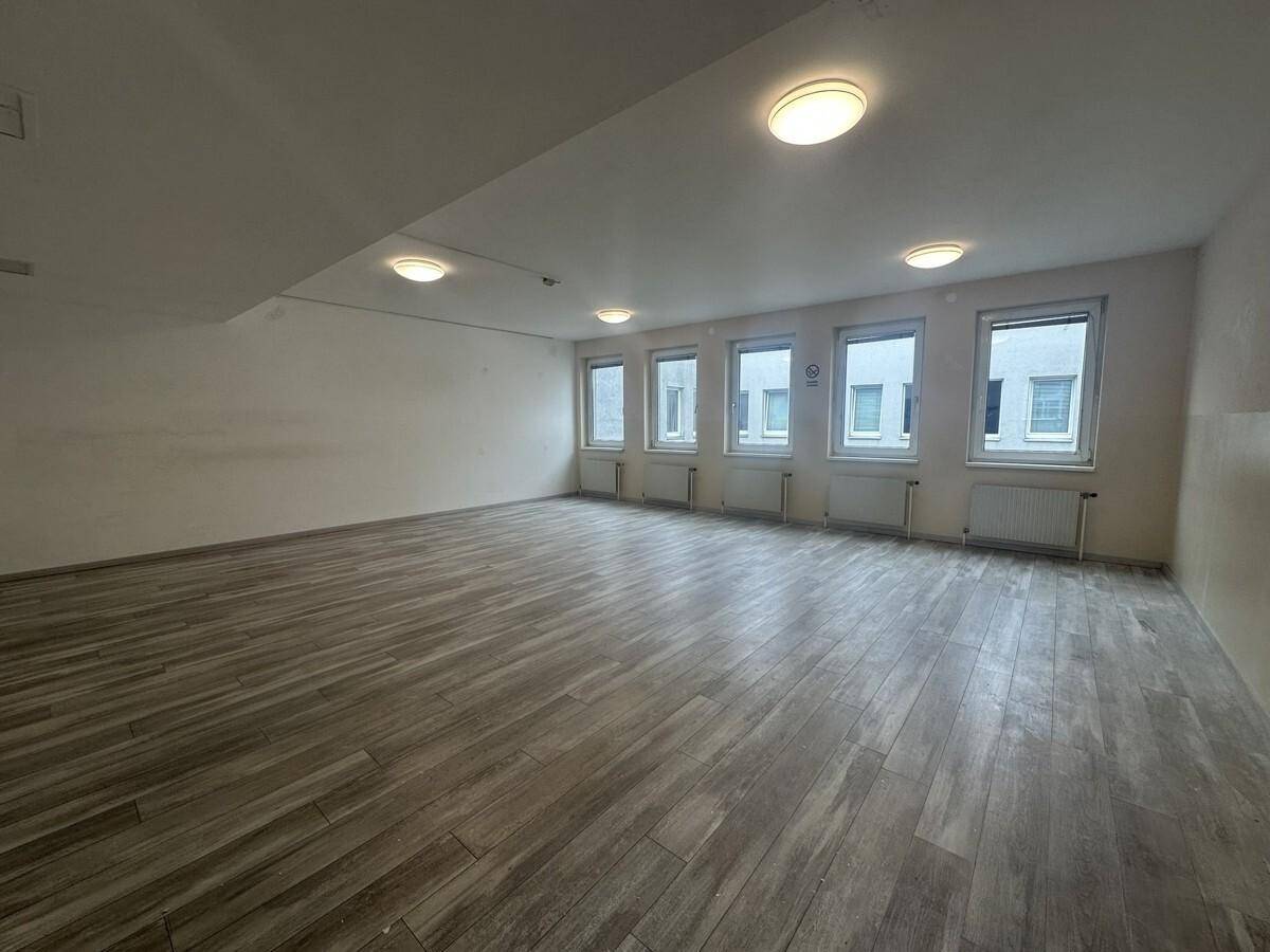 Helles Büro mit modernem Laminatboden und einer Reihe von Fenstern, die den Raum belichten.