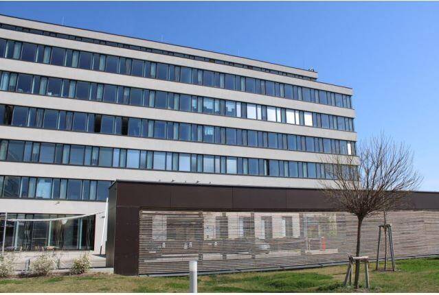 Modernes Bürogebäude mit vielen Fenstern und einer ansprechenden Fassadengestaltung unter blauem Himmel.