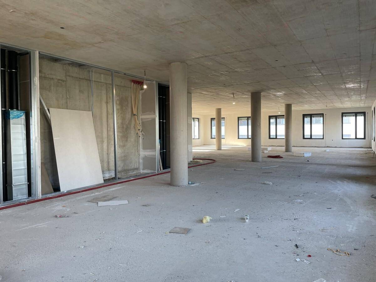 Großer, unfertiger Büroraum mit Betonboden, Säulen und Metallständern für die Wandkonstruktion.