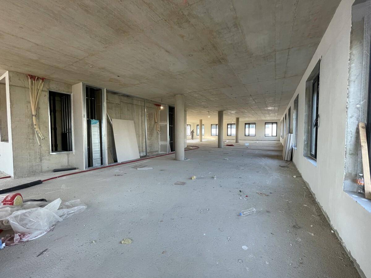 Weitläufiger, unfertiger Büroraum mit Betonoberflächen, Säulen und vorbereiteten Wandstrukturen.