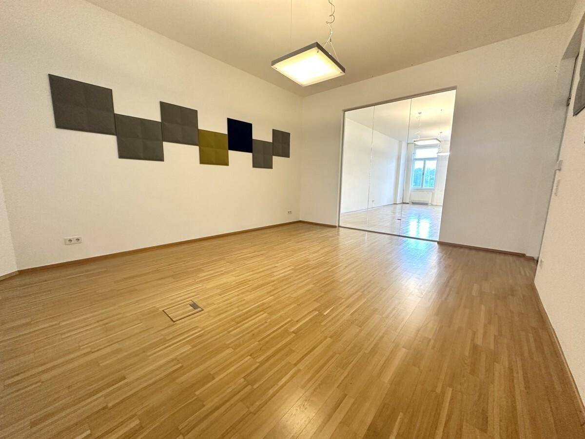Großer Bürobereich mit Holzboden und mehreren modernen Glasabtrennungen zu weiteren Räumen.