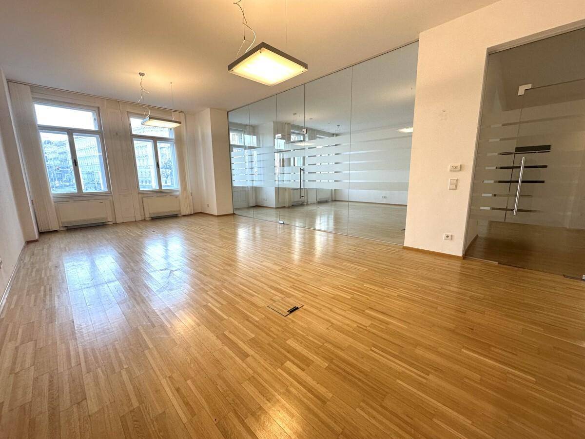 Büroraum mit Holzboden, weißer Wand und dekorativen Akustikpaneelen, mit Spiegelwand.