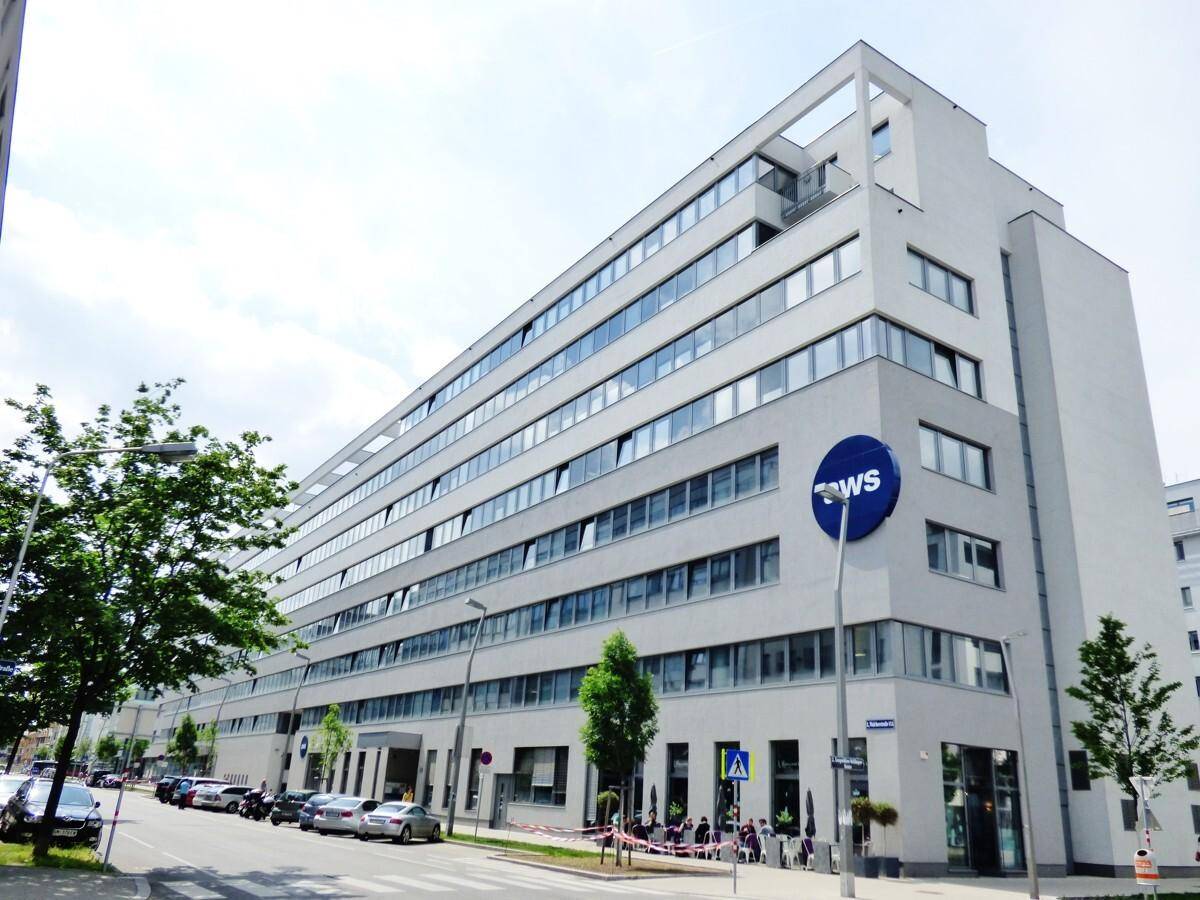 Weitläufiges Bürogebäude mit moderner Architektur und großen Fensterfronten unter bewölktem Himmel, an einer Straße gelegen.