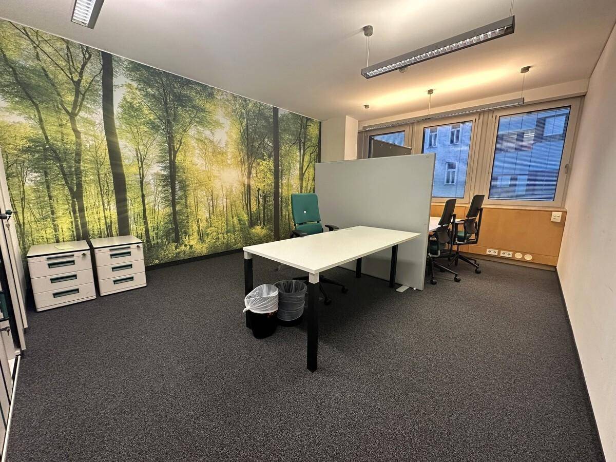 Büroarbeitsplatz mit Schreibtischen und Aktenschränken, belebt durch eine große Wandtapete mit einem Waldmotiv.
