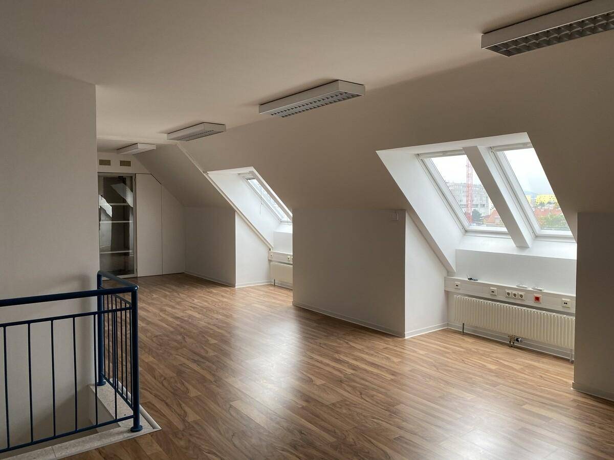 Heller Dachgeschossraum mit schrägen Decken, Dachfenstern und Holzparkettboden, ideal als Wohnbereich.