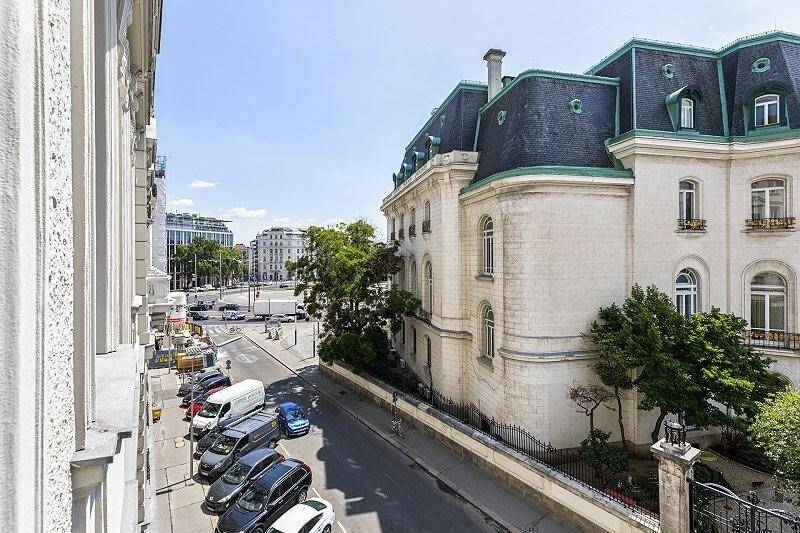 Ansicht eines historischen Gebäudes mit Mansarddach und belebter Straße davor in der Stadt.