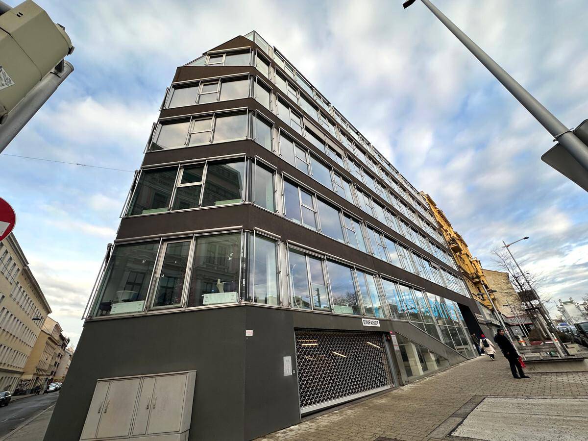 Modernes Bürogebäude mit markanter Architektur, vielen Glasflächen und einer Rolltor-Einfahrt.