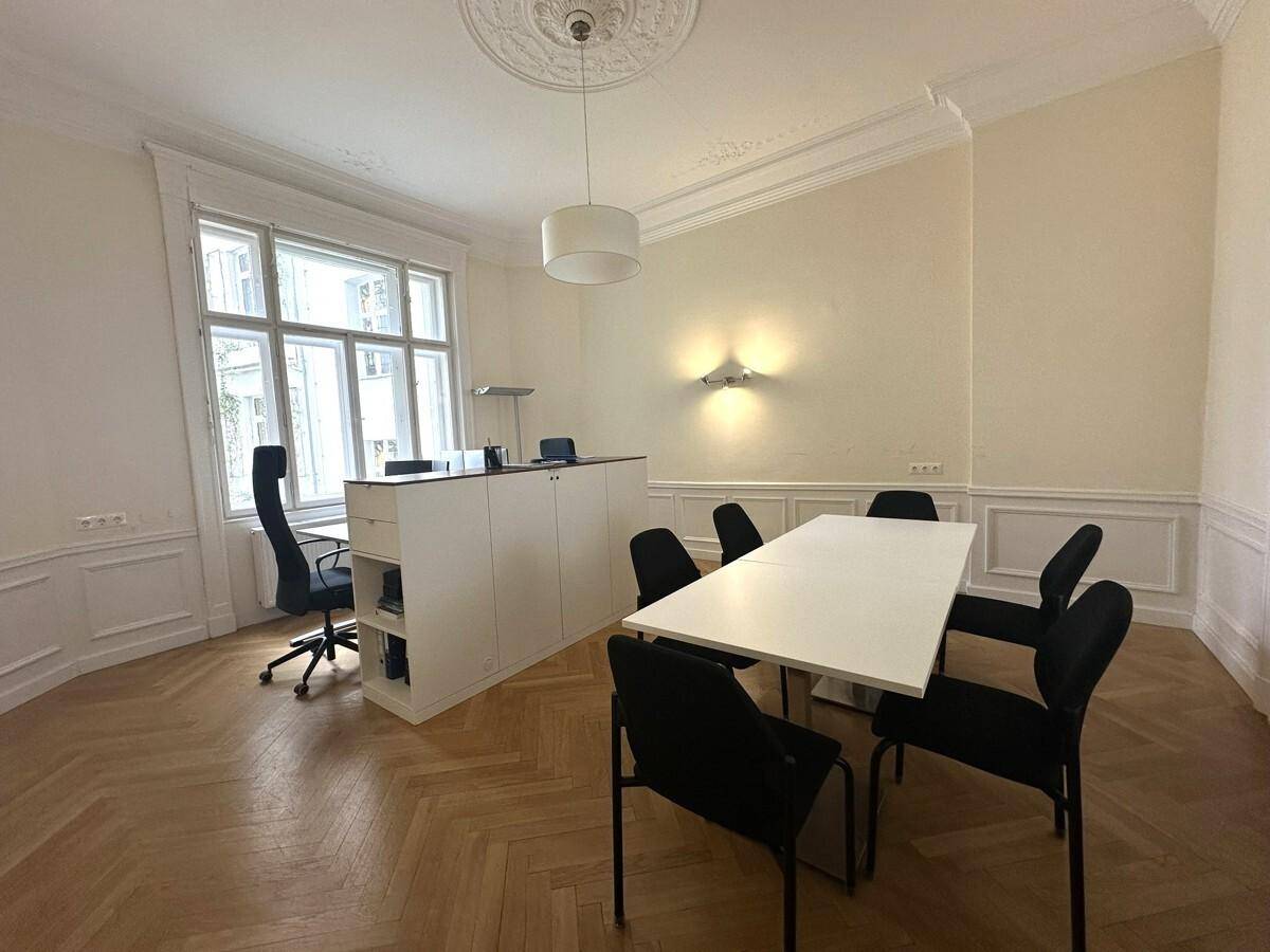 Elegantes Büro oder Konferenzzimmer mit großem Tisch, Fischgrätparkett und Stuckverzierungen an der Decke.