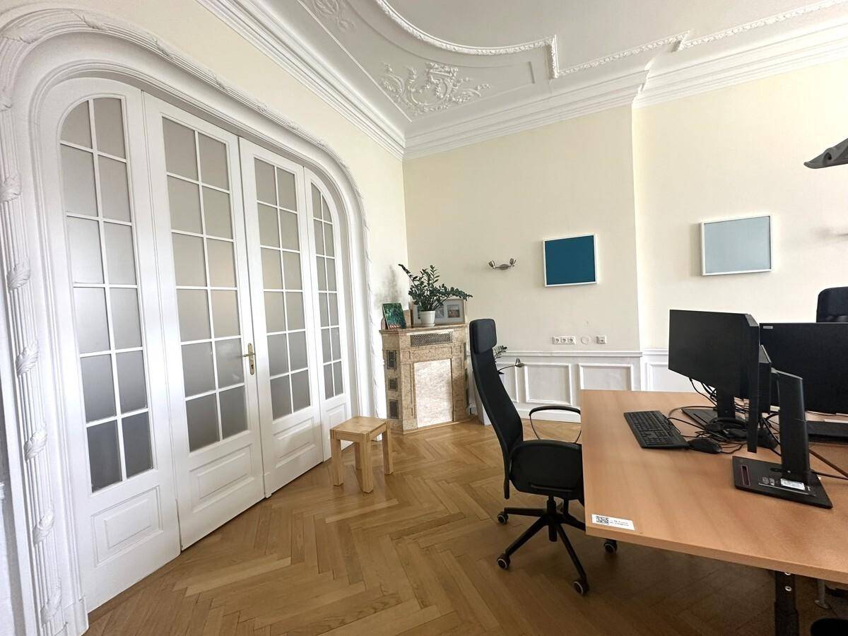 Stilvolles Büro mit Schreibtisch, Computer und eleganten Flügeltüren, ergänzt durch Fischgrätparkett und Kamin.
