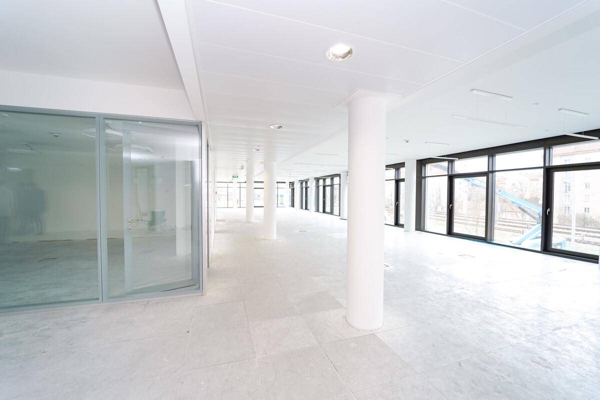 Geräumiger, heller Bürobereich mit Säulen und Glaswänden für flexible Raumgestaltung.