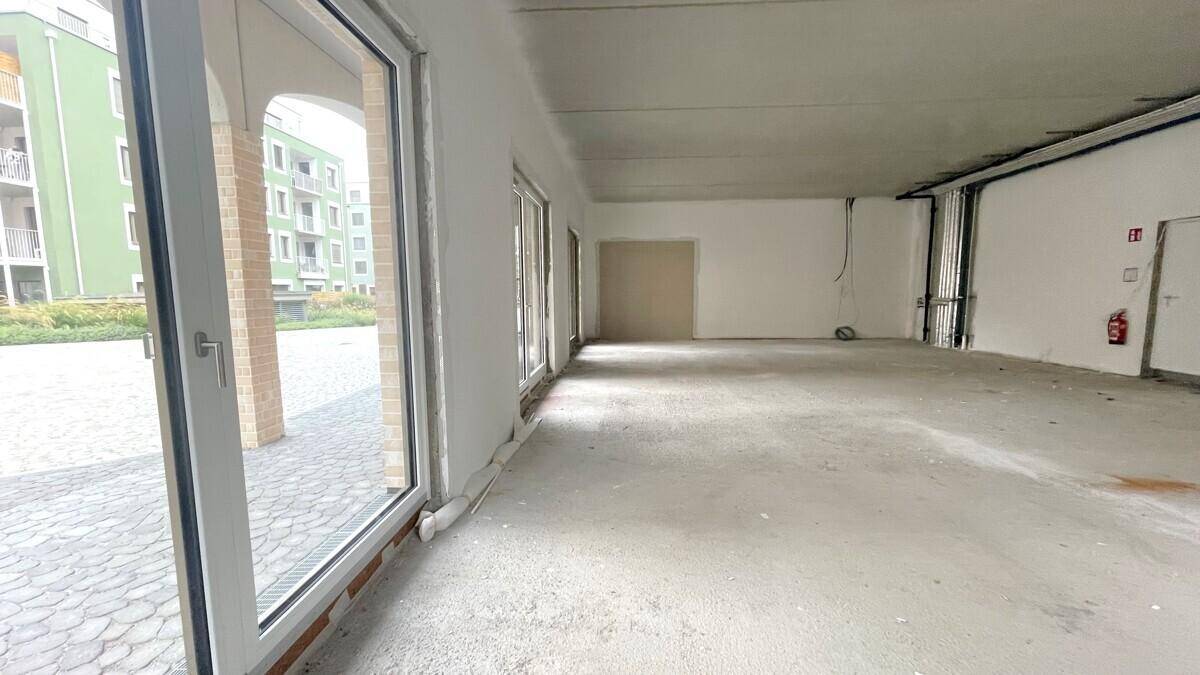 Heller Gewerberaum mit großen Schaufenstern und Blick auf die umliegenden Gebäude.