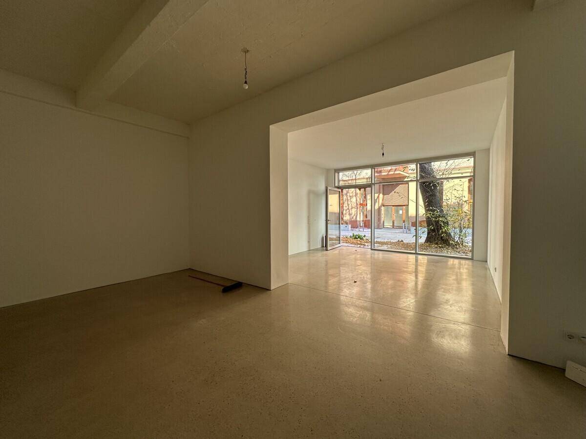 Geräumiger, leerer Gewerberaum mit großen Fenstern und Betonboden, bereit für den Ausbau.
