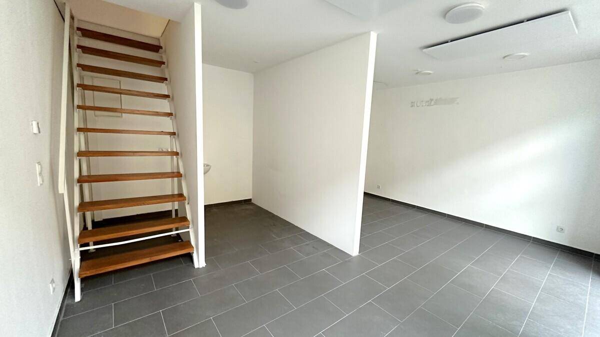 Innenansicht eines Geschäftsraums mit Holztreppe und Trennwand, bereit für die individuelle Gestaltung.