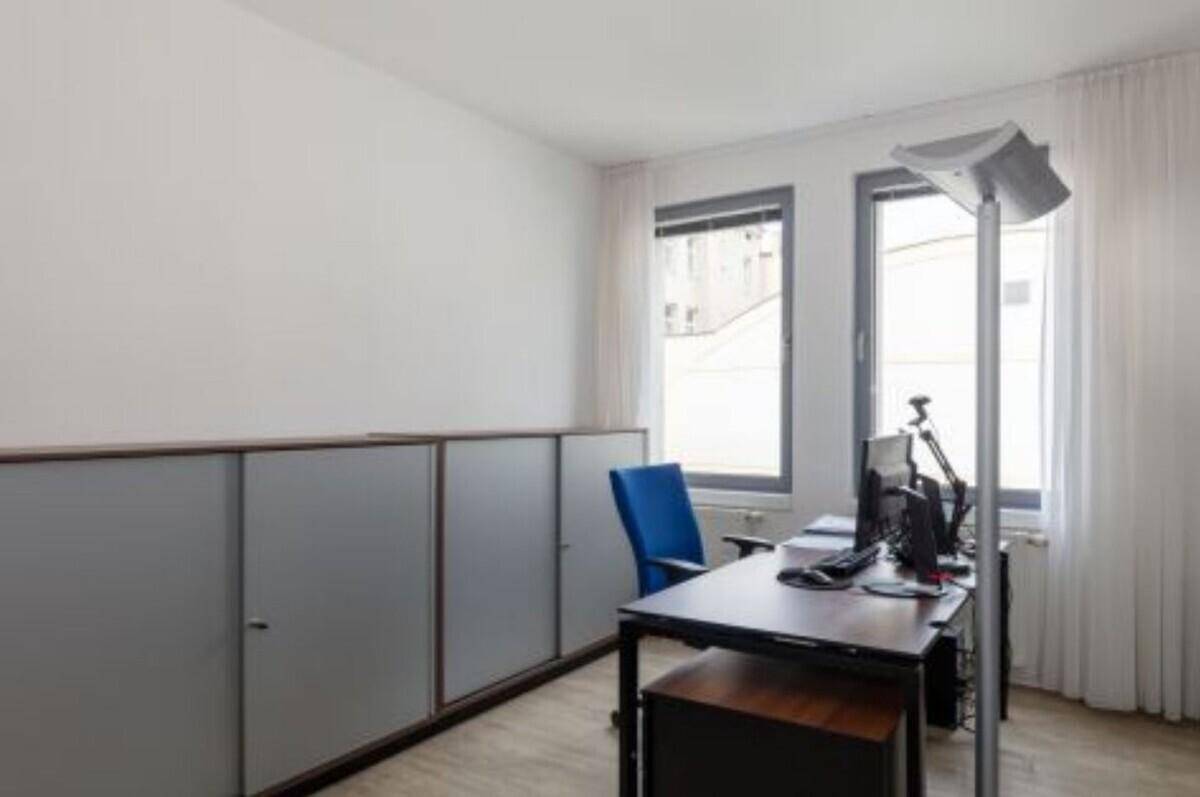 Einzelbüro mit Schreibtisch, Bürostuhl und langen Schränken entlang der Wand.