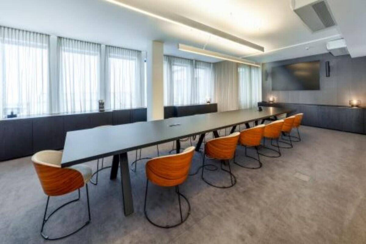 Großer Konferenzraum mit langem Tisch, modernen Stühlen und vielen Fenstern.