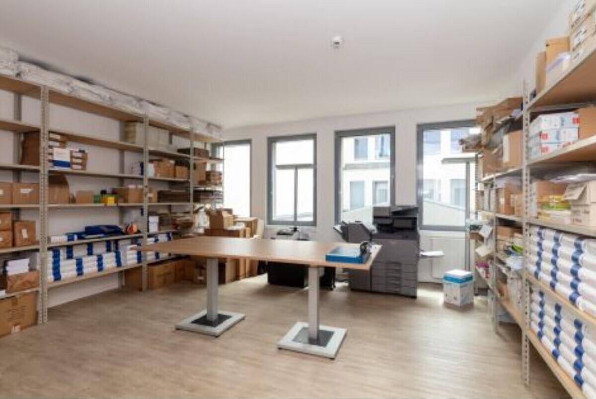 Lagerraum mit Regalen voller Kartons, einem Tisch und Fenstern.