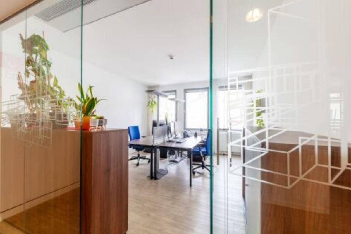Modernes Büro mit Glaswänden, mehreren Arbeitsplätzen und viel Tageslicht.