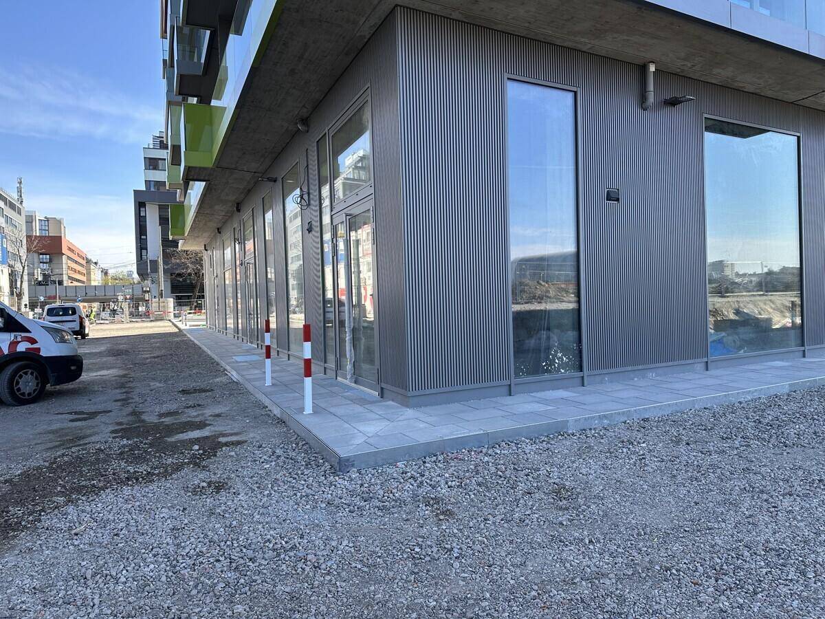 Eckbereich der Gewerbeflächen im Erdgeschoss mit großen Schaufenstern und moderner Fassadenverkleidung.