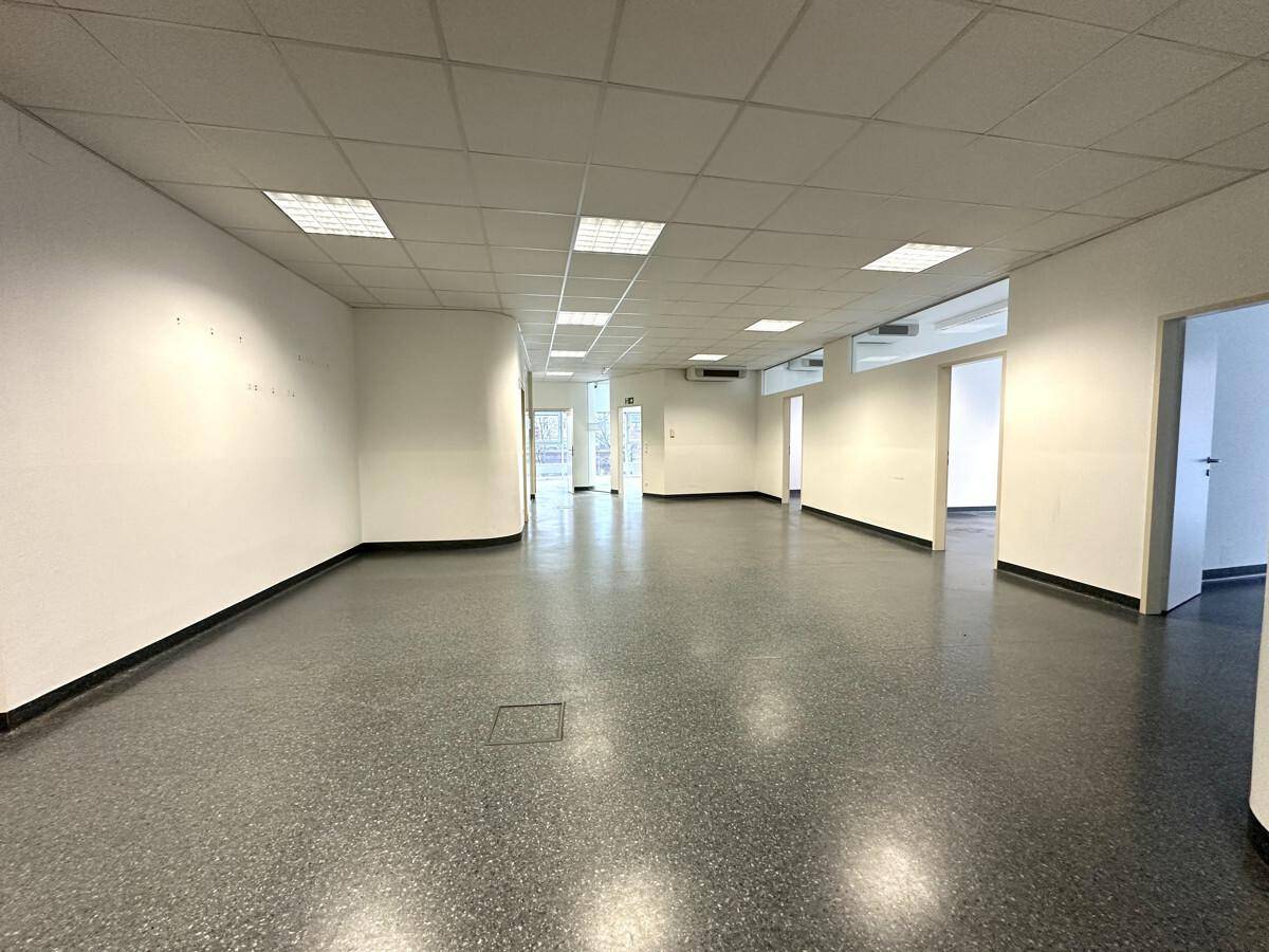 Langer, leerer Bürogang mit mehreren Türen, Deckenbeleuchtung und Klimaanlage.