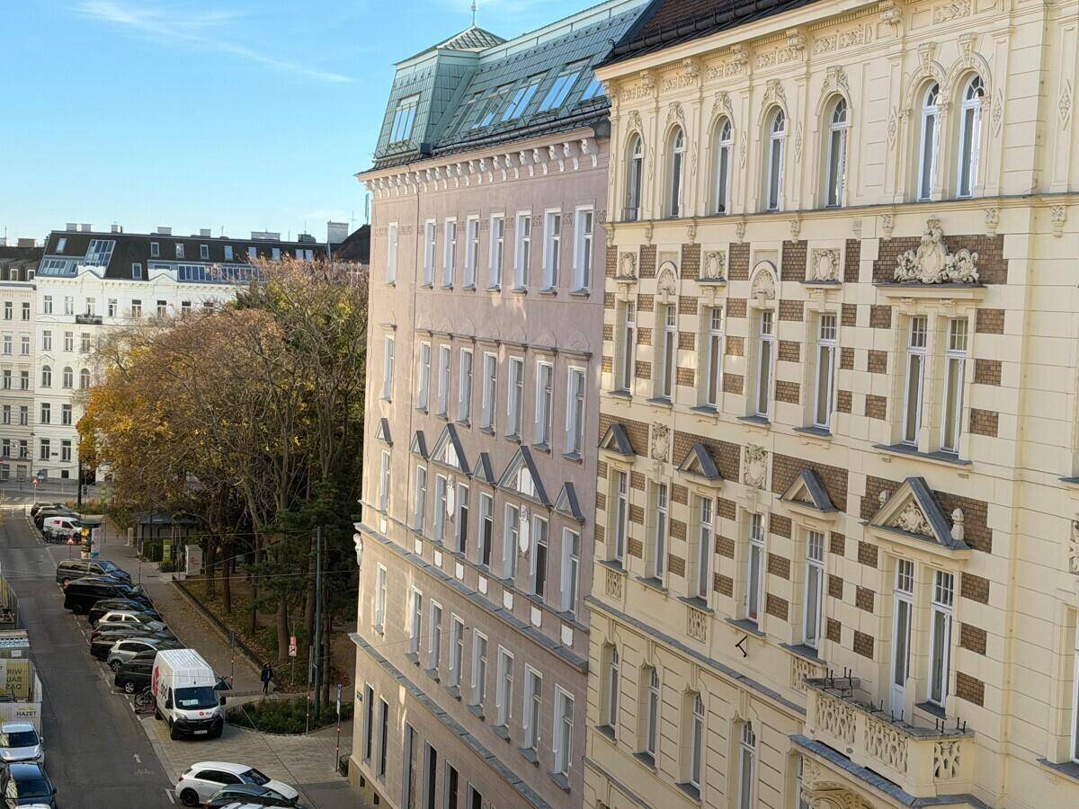Historische Gebäude mit reich verzierten Fassaden und einer belebten Straße davor unter blauem Himmel.