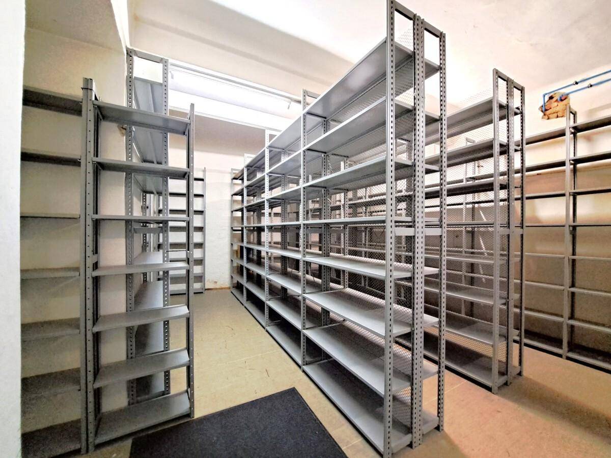 Geräumiger Kellerraum mit robusten Metallregalen, ideal für Lagerung und Archivierung von Materialien.