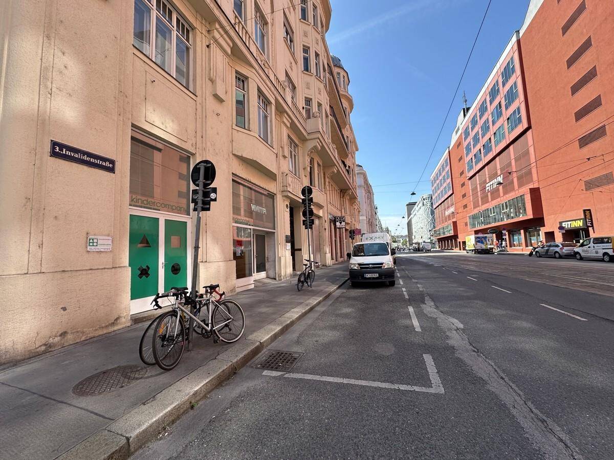 Weitläufige Straßenansicht mit historischen Gebäuden und modernen Bauten unter blauem Himmel.