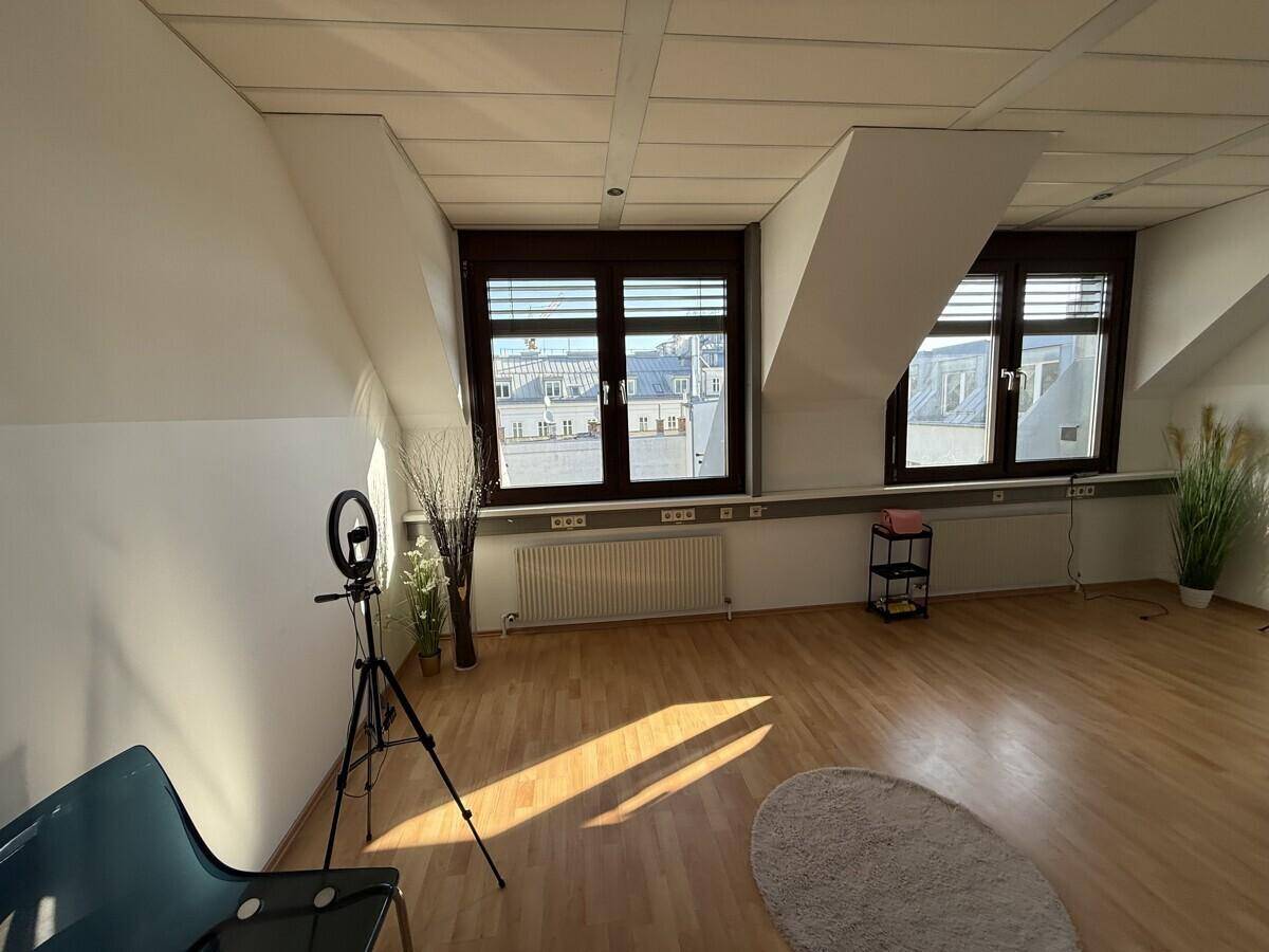 Heller Büroraum mit Holzboden, großen Fenstern und Dachschrägen, ideal für kreative Arbeitsbereiche.