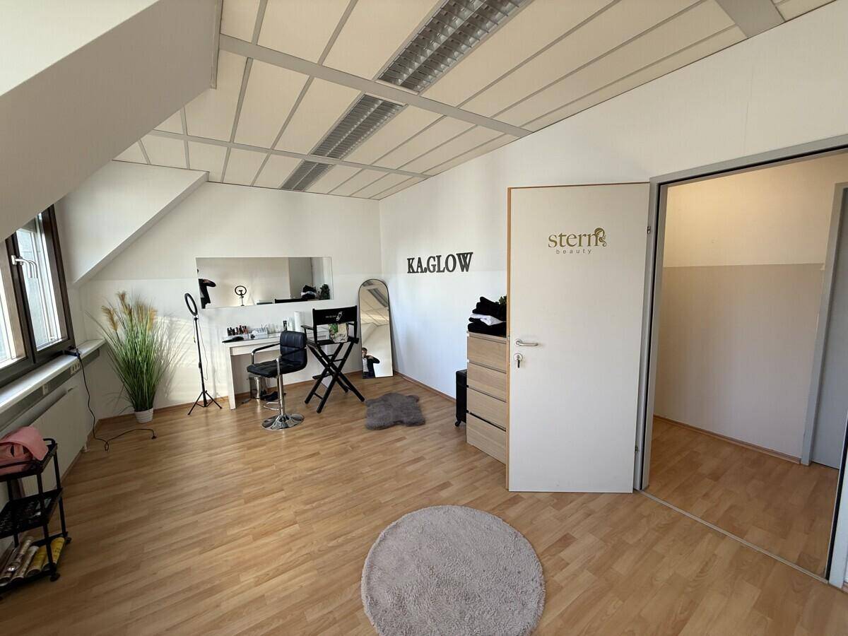 Büroraum mit Holzboden, Dachschrägen und einem Schminktisch, der als Beauty-Studio genutzt wird.