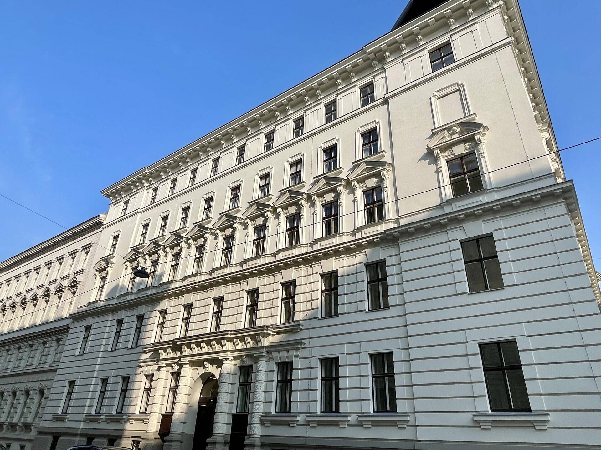 Seitenansicht eines eleganten Altbaus mit zahlreichen Fenstern und detaillierter Fassadengestaltung.