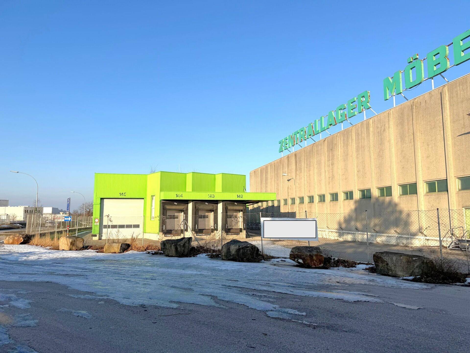Grüne Laderampen an einem Lagergebäude mit der Aufschrift "ZENTRALLAGER MÖBEL" und Schnee auf dem Boden.