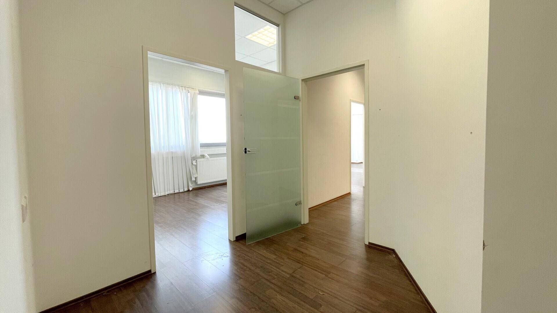 Heller Flur mit Holzboden und mehreren Türen, die zu verschiedenen Büroräumen führen.
