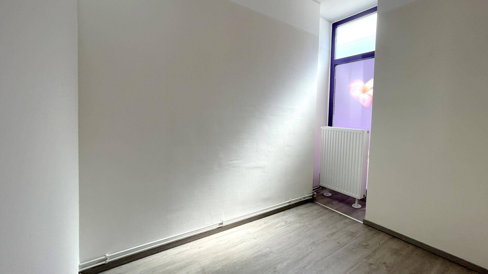 Heller Raum mit weißen Wänden und einem Fenster mit Blumenmotiv, das natürliches Licht hereinlässt.