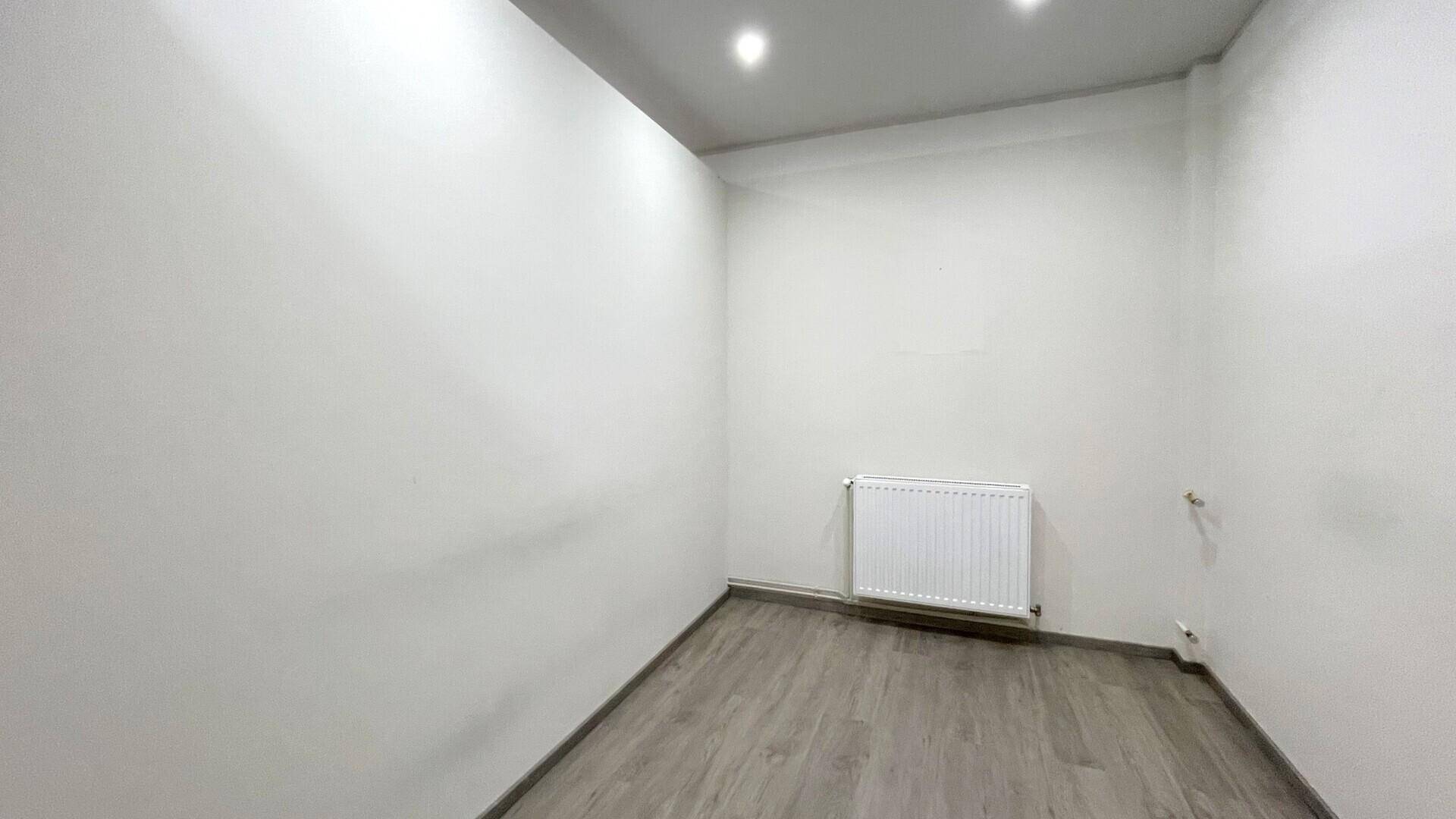 Kleiner, heller Büroraum mit weiß gestrichenen Wänden, Heizkörper und modernem Holzboden.