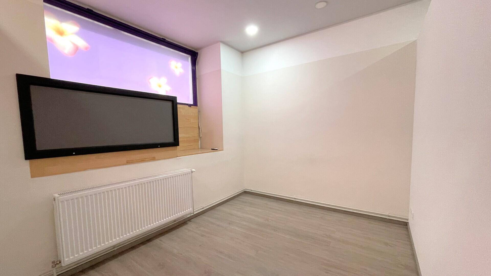 Büroraum mit einem großen Fenster, das mit einer Folie beklebt ist, und einem Heizkörper darunter.